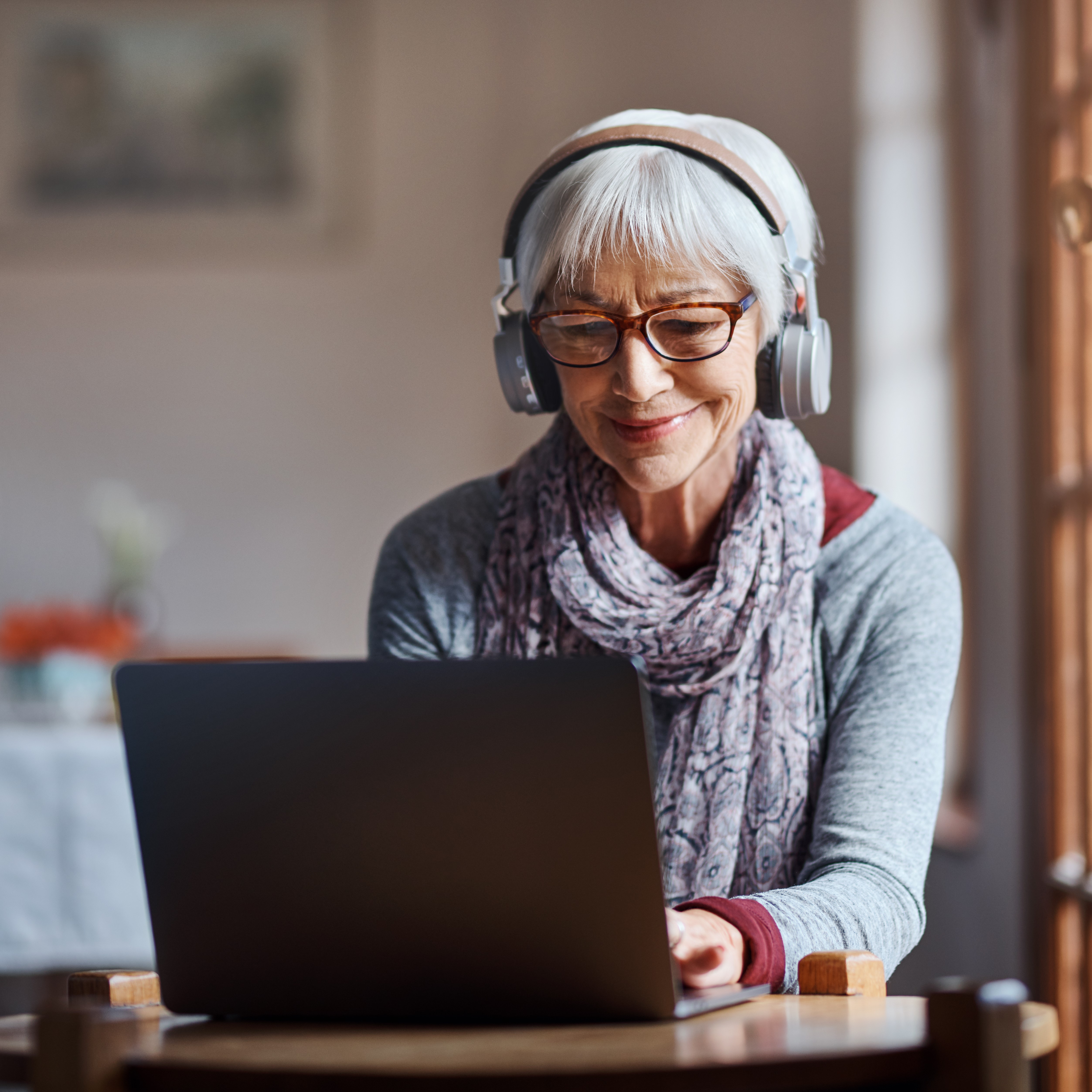 Senior woman wearing headphones at laptop